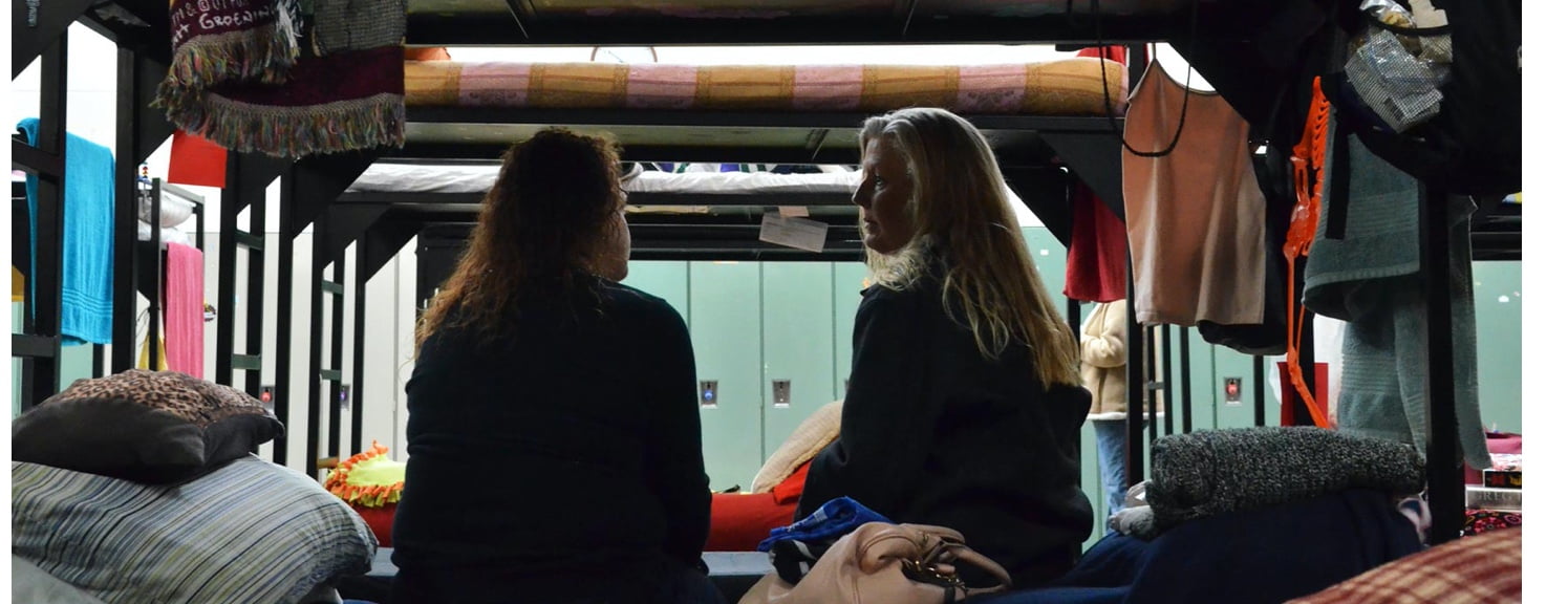 Two women sitting on a bed