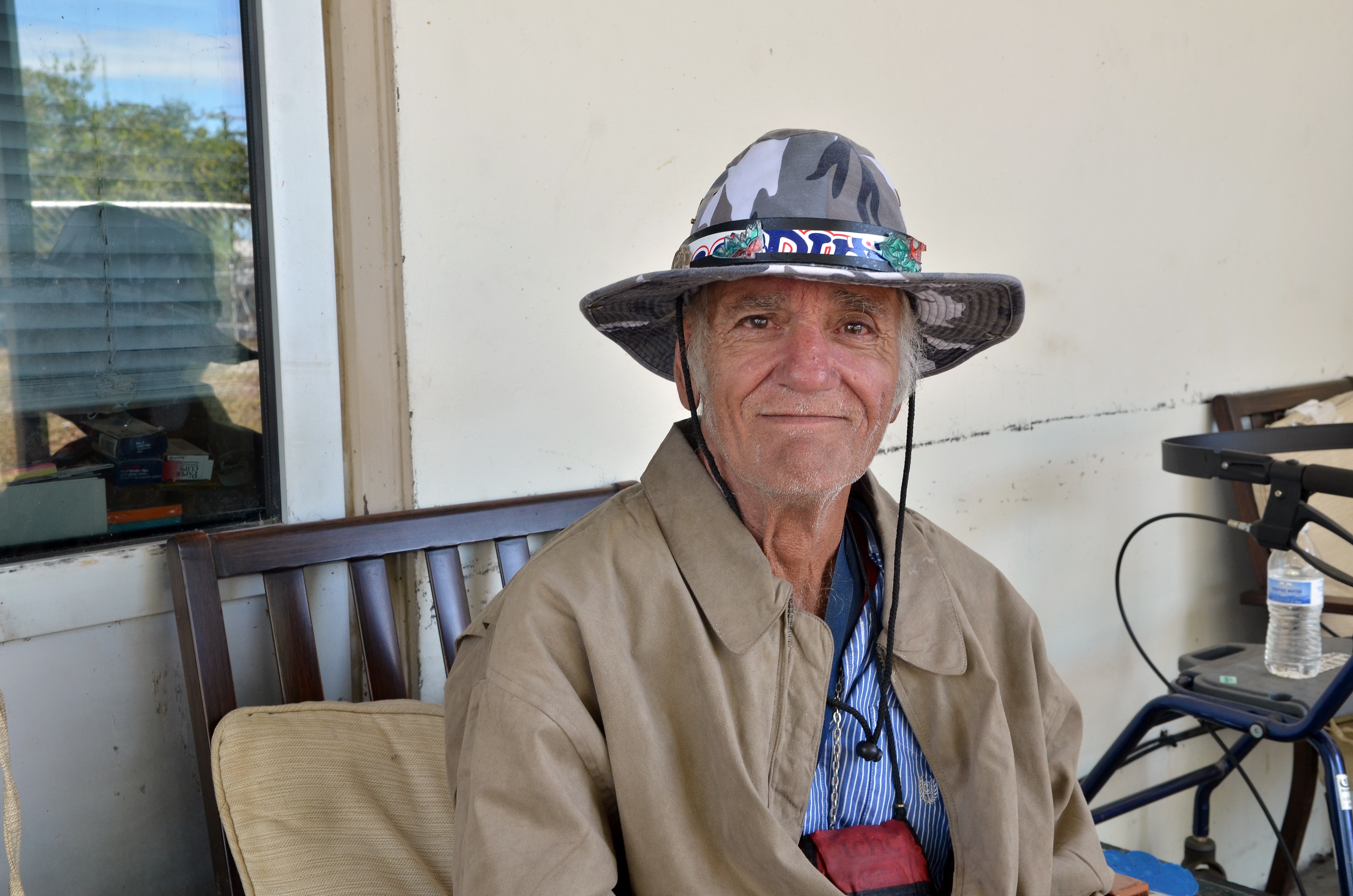 a veteran wearing a hat smiles at the camera