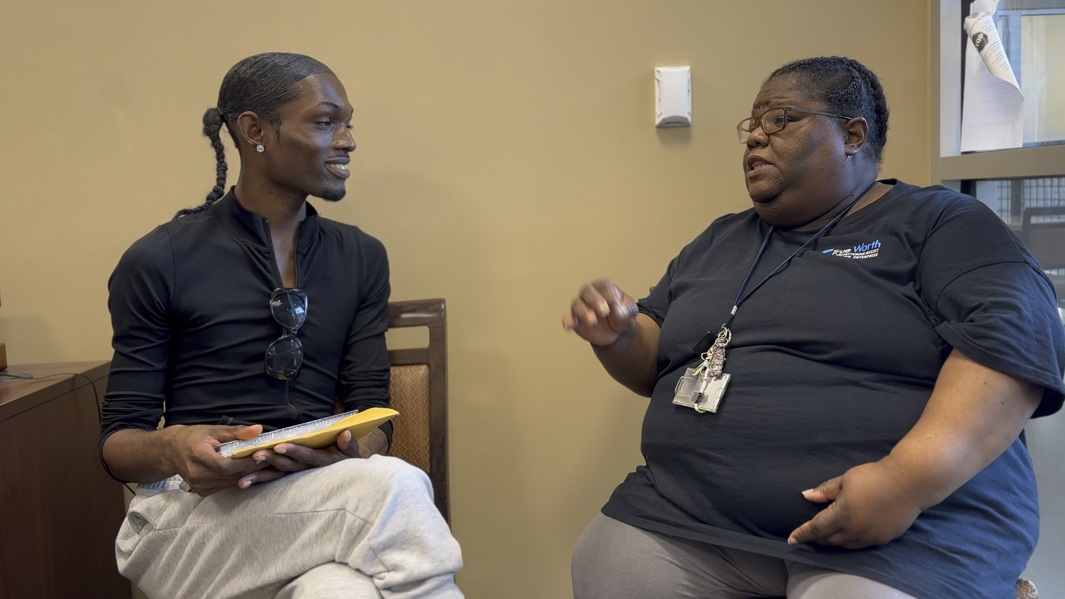 A man and a woman sit at chairs having a conversation.