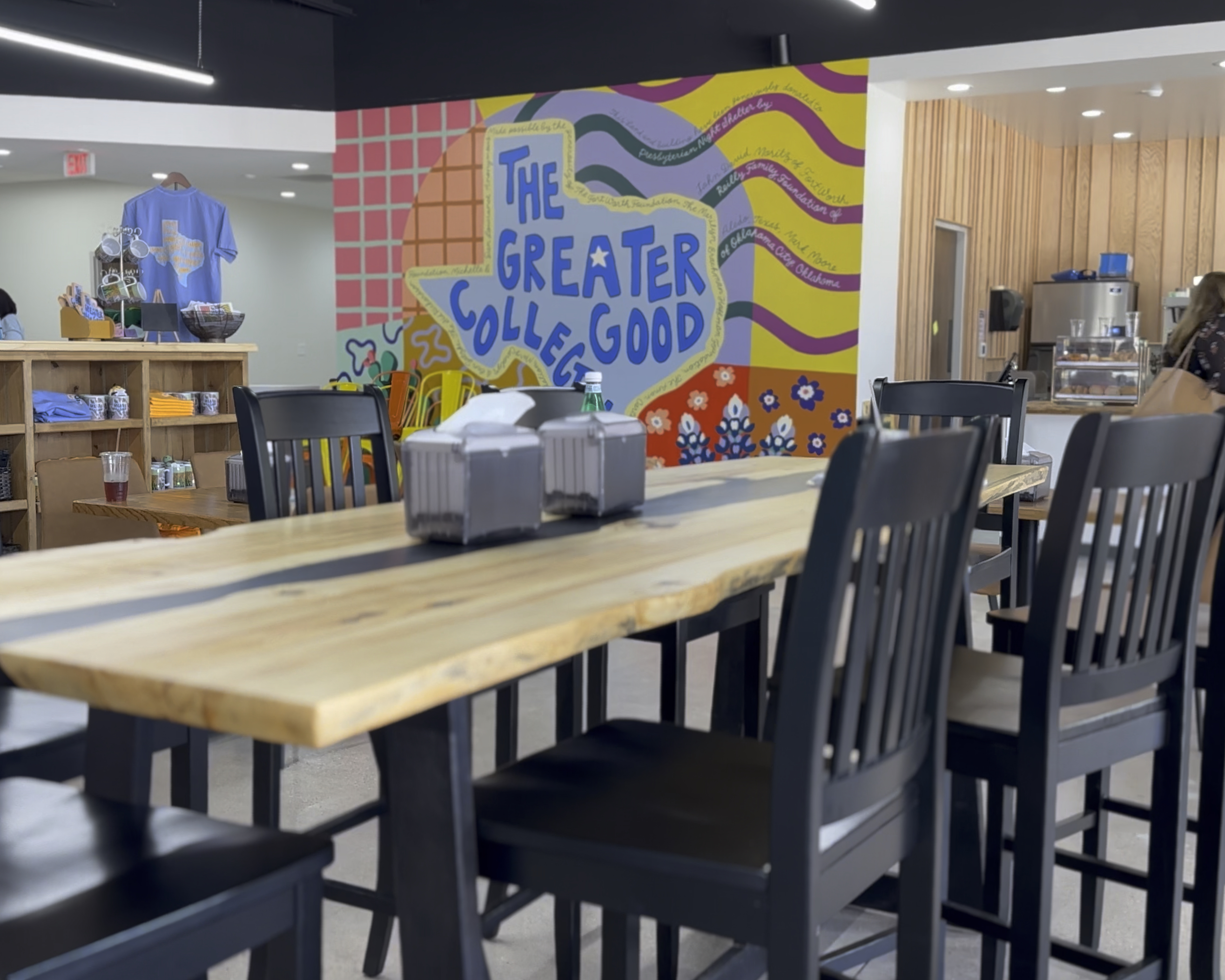 Interior shot of Greater Good Collective. A colorful mural is on the back wall.